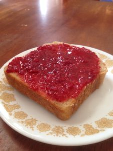 Slice of home made bread with raspberry jam.